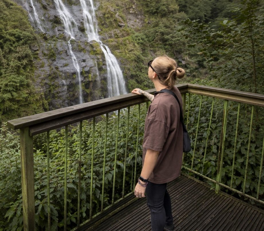 Sarah “Sy” Taylor standing beside a rainforest waterfall, founder of The Inner Growth Path.