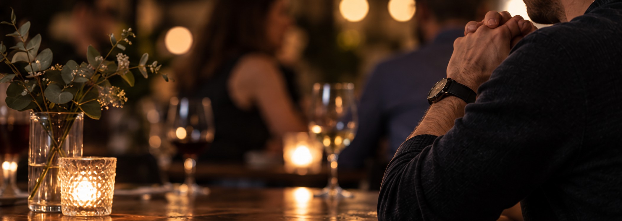 A man sitting quietly in a restaurant with his hands clasped tightly near his face survival mode